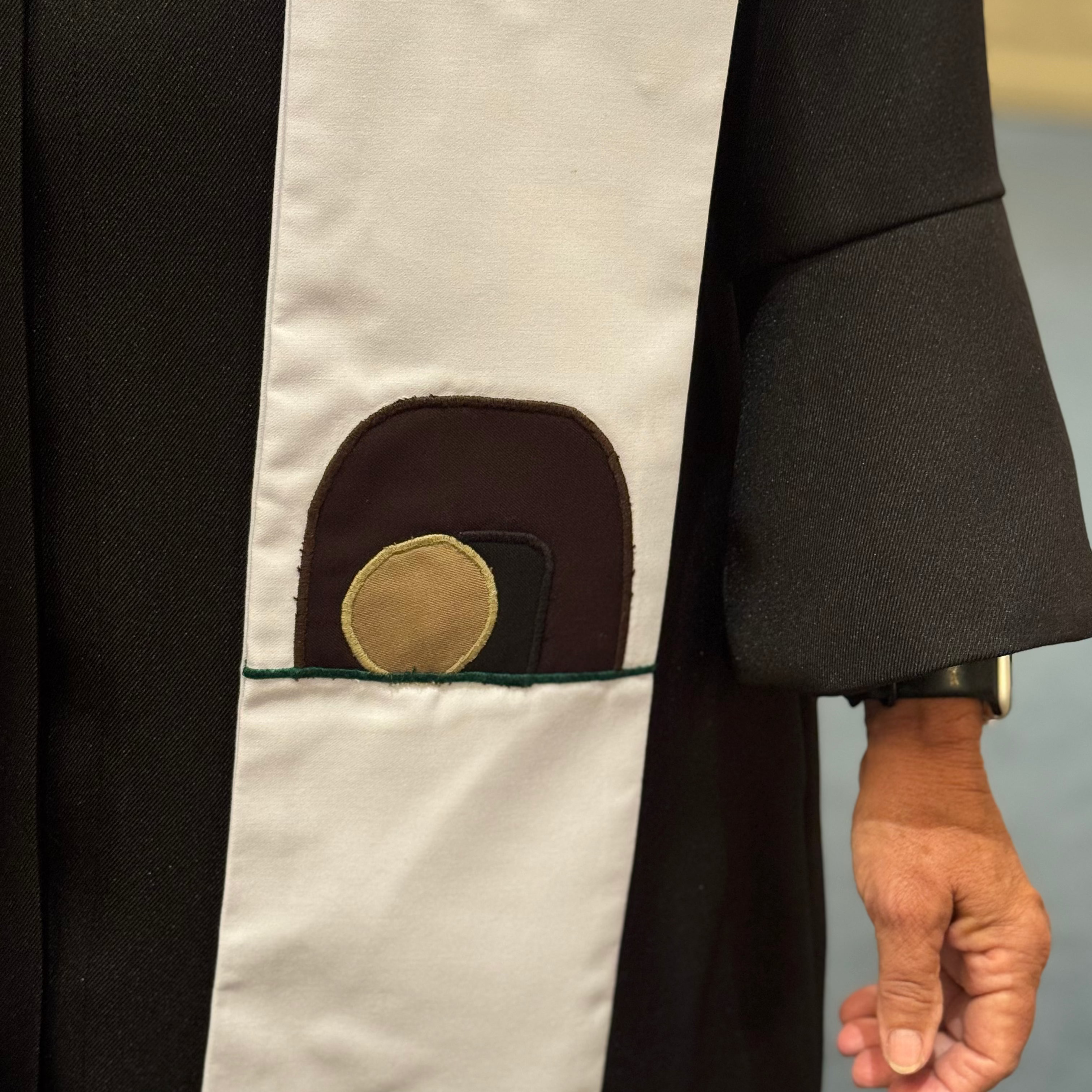 Close-up of a black and white garment with a brown circular patch on a neutral background