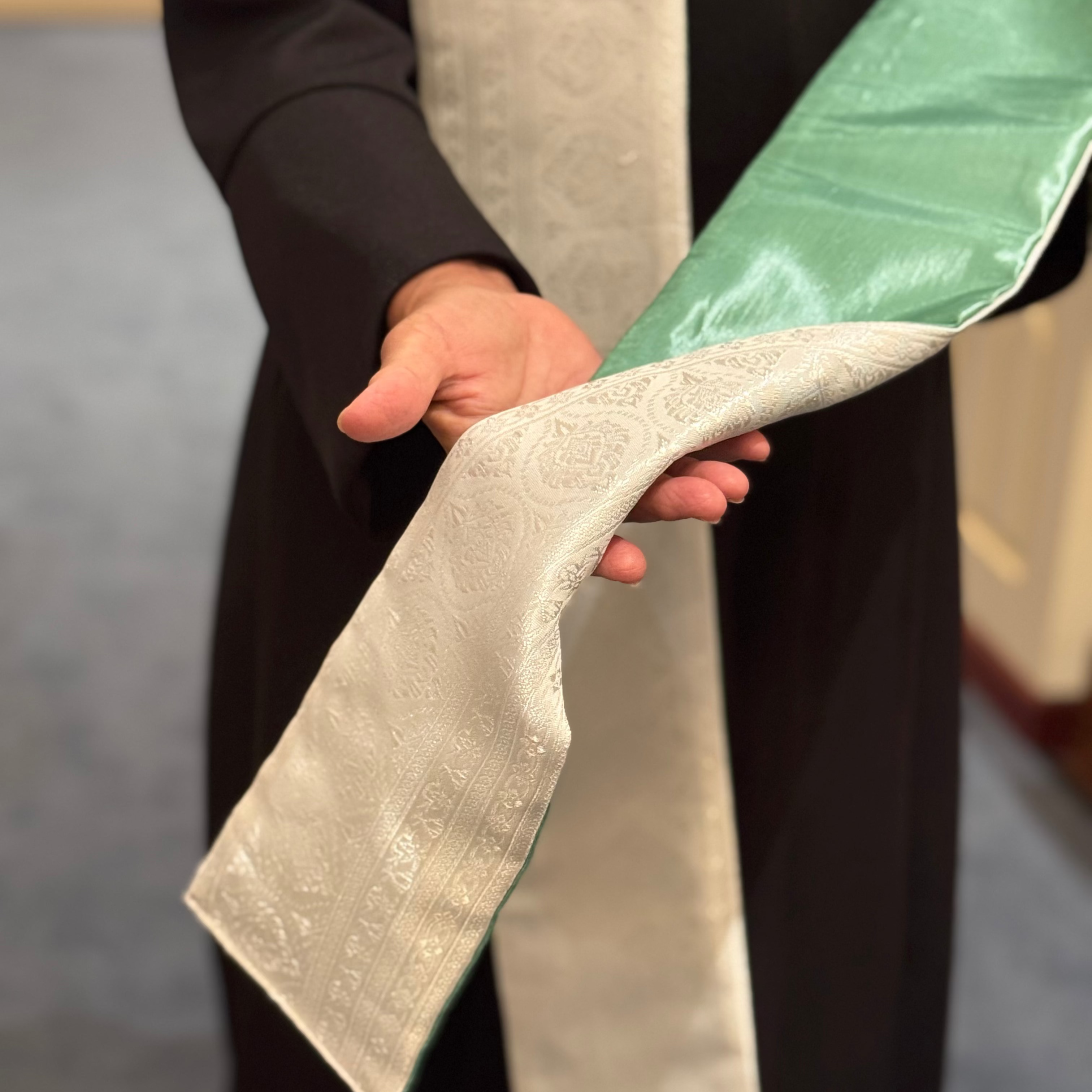 Person holding a green and gray sash with a blurred background